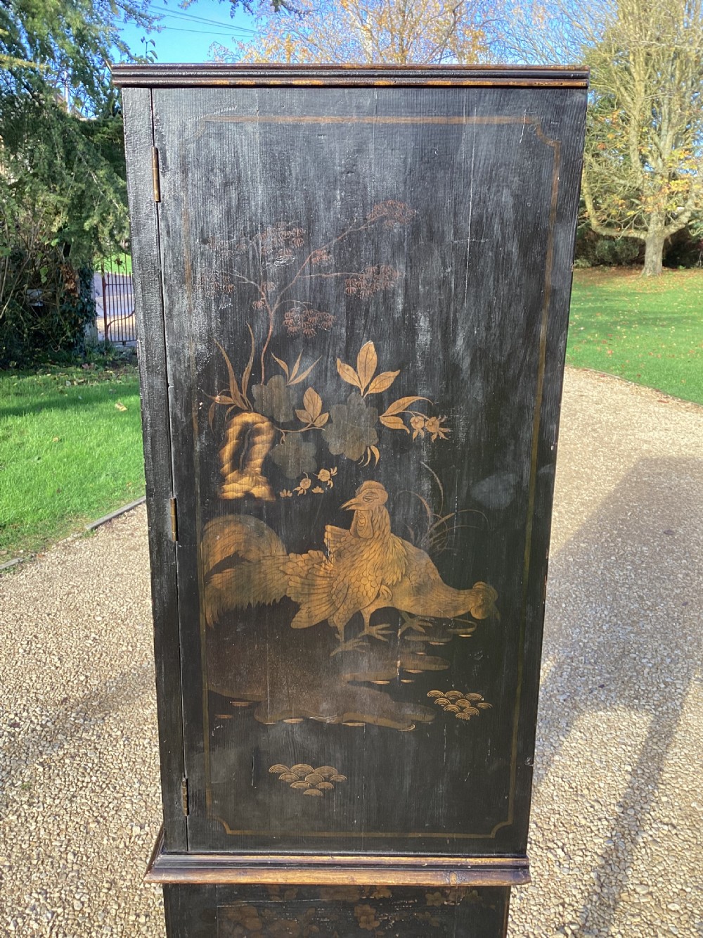 A Regency period black lacquer cabinet on stand, featuring gilt Chinoiserie landscape and floral scenes, open double doors, and fitted internal drawers surrounding a central panel. View VIII