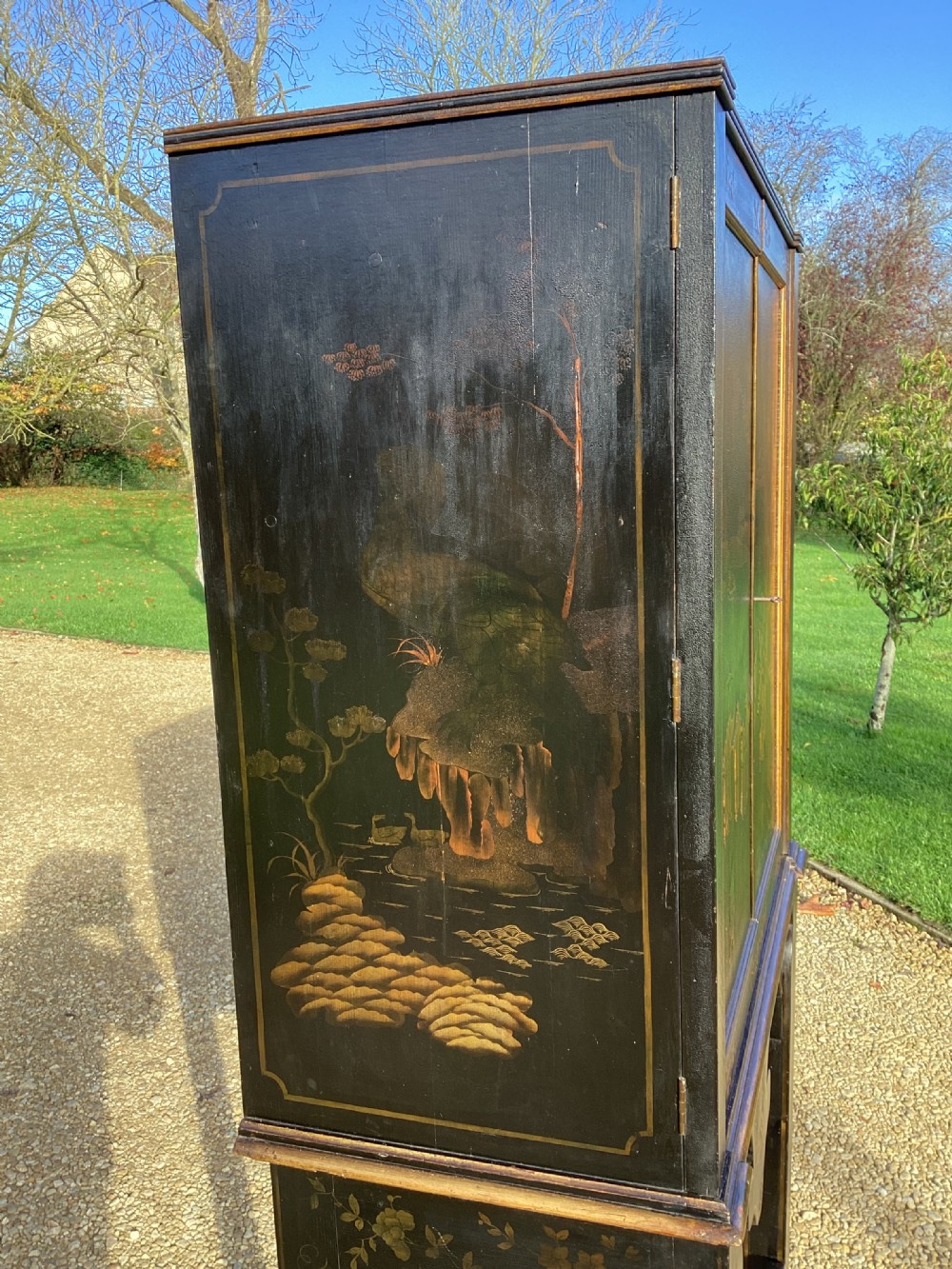 A Regency period black lacquer cabinet on stand, featuring gilt Chinoiserie landscape and floral scenes, open double doors, and fitted internal drawers surrounding a central panel. View IX