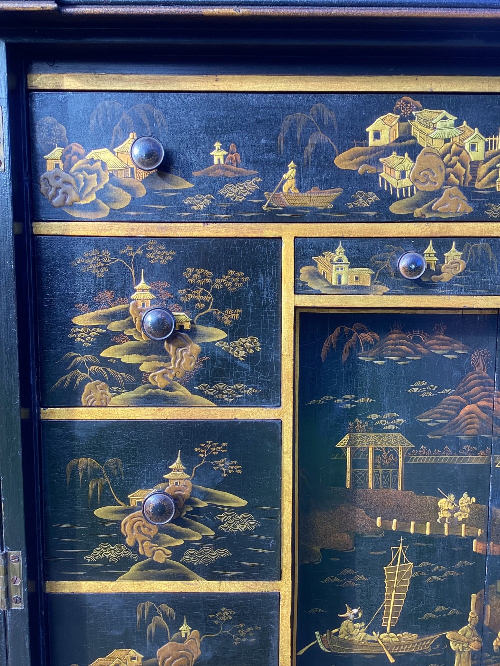 A Regency period black lacquer cabinet on stand, featuring gilt Chinoiserie landscape and floral scenes, open double doors, and fitted internal drawers surrounding a central panel. View XII