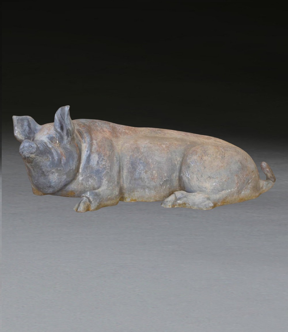 A 19th-century cast lead sculpture of a recumbent pig featuring a weathered grey finish and textured surface details.