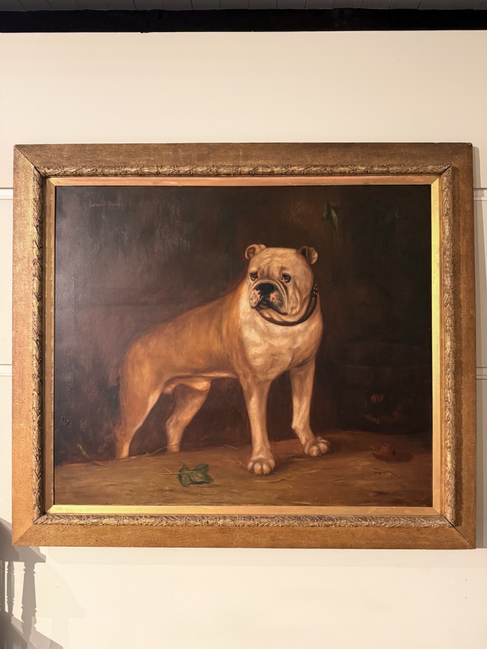 A 19th-century oil painting depicting a standing bulldog in a dark interior, displayed within a carved gilt wooden frame.