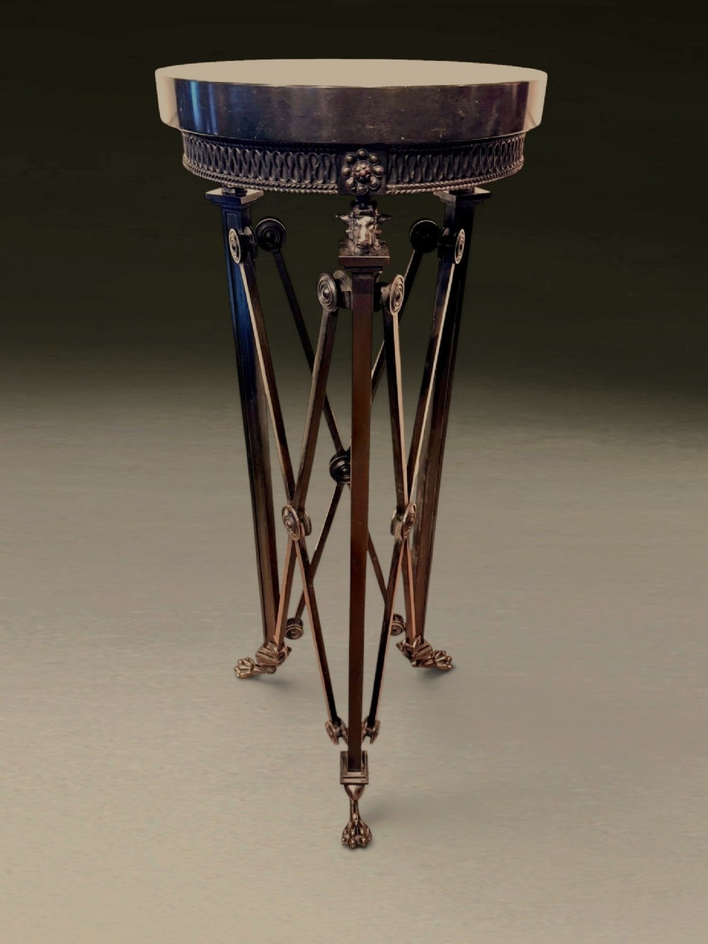 A tall Regency dark patinated bronze tripod stand featuring a circular marble top, classical roundels, crossed leg supports, and lion paw feet.
