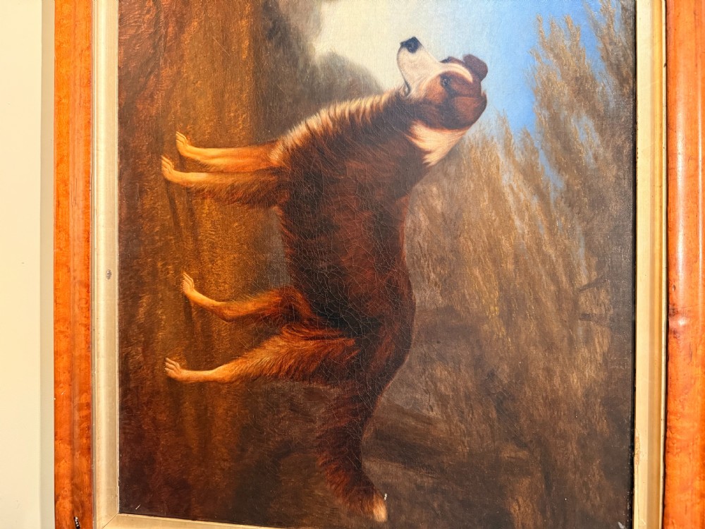A 19th-century primitive oil painting on canvas depicting a standing brown and white dog set against a landscape backdrop, housed within a wide wood frame. View III