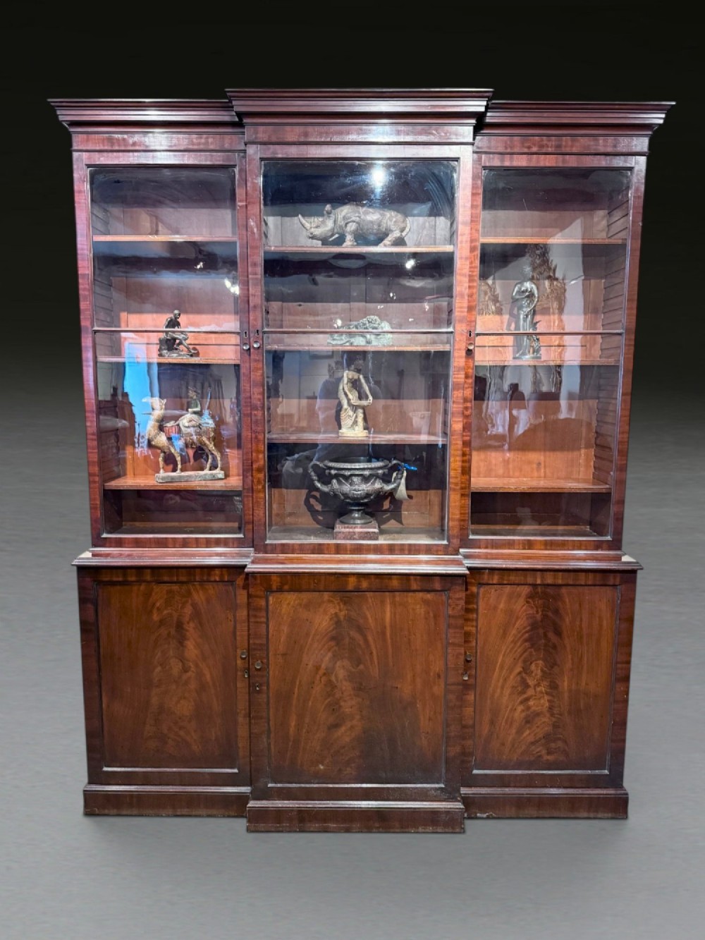 A Georgian flame mahogany breakfront bookcase featuring glazed upper doors and panelled lower cupboard doors.