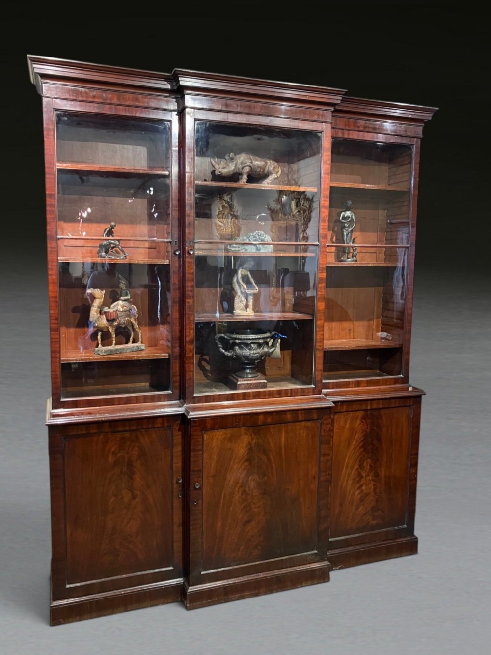 A Georgian flame mahogany breakfront bookcase featuring glazed upper doors and panelled lower cupboard doors. View II