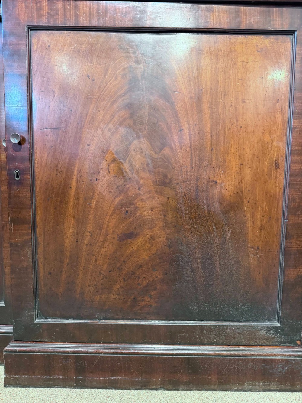 A Georgian flame mahogany breakfront bookcase featuring glazed upper doors and panelled lower cupboard doors. View V