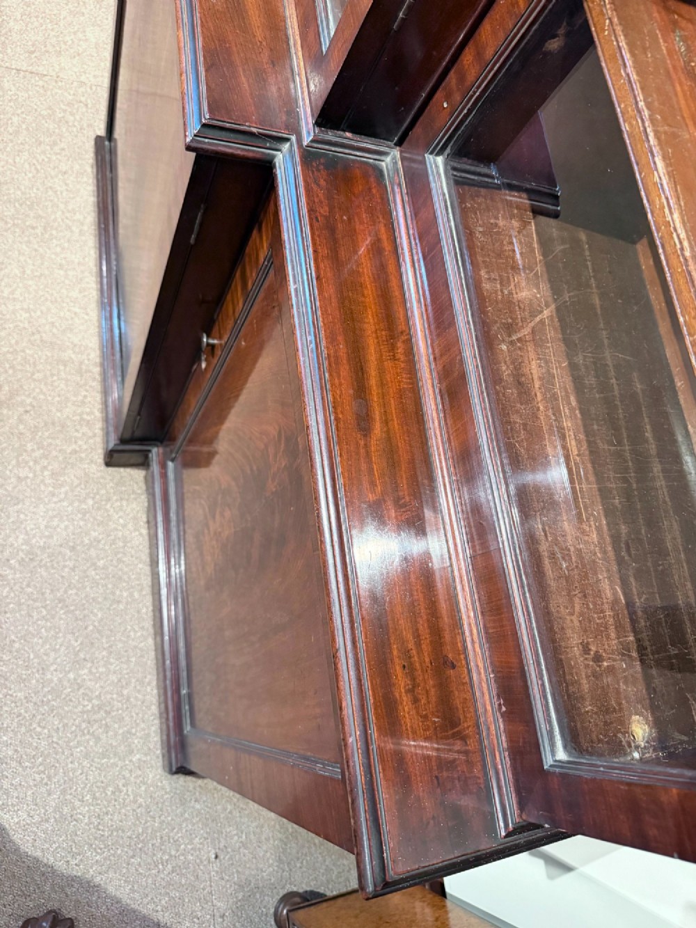 A Georgian flame mahogany breakfront bookcase featuring glazed upper doors and panelled lower cupboard doors. View VIII