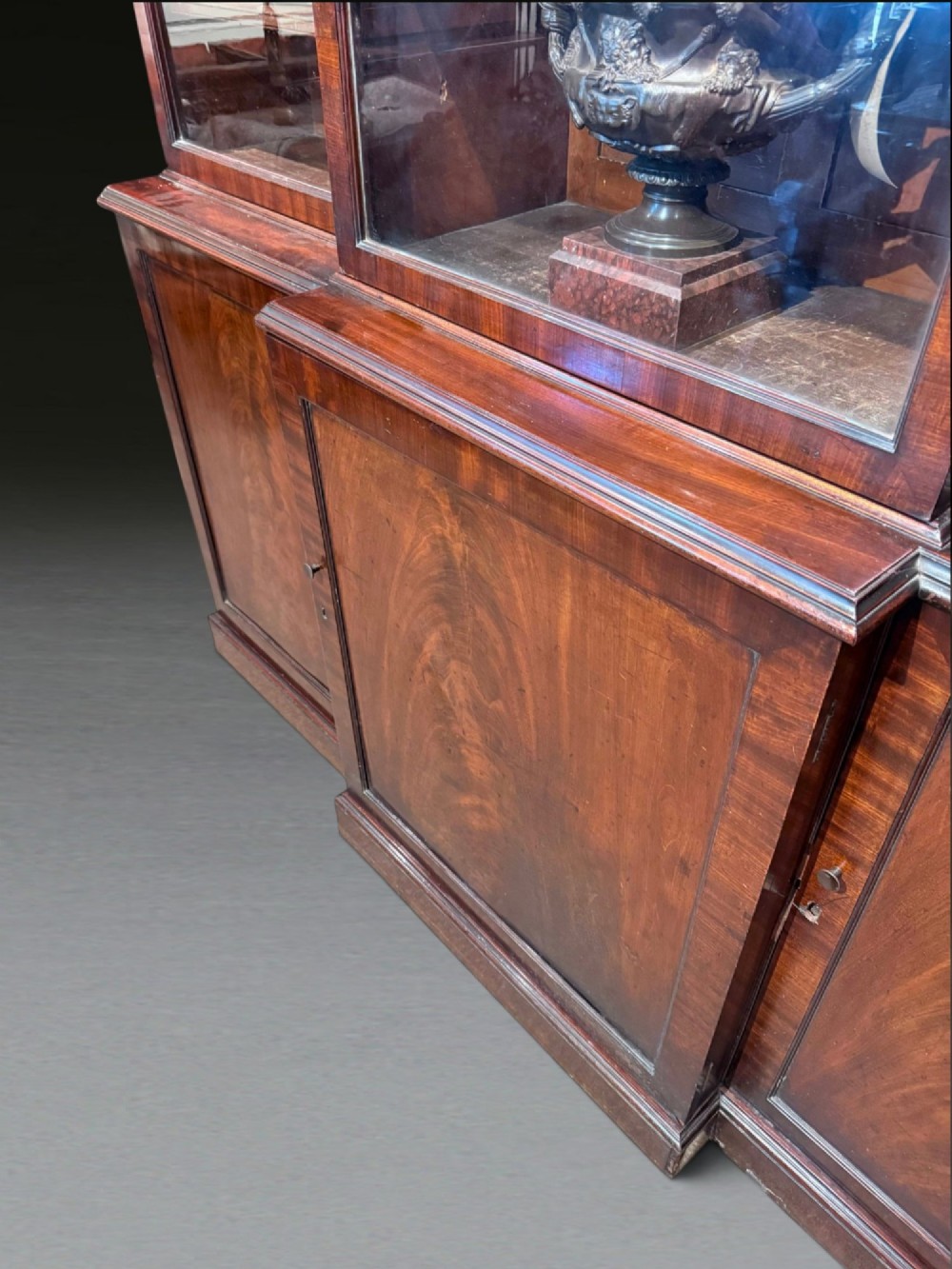 A Georgian flame mahogany breakfront bookcase featuring glazed upper doors and panelled lower cupboard doors. View IX