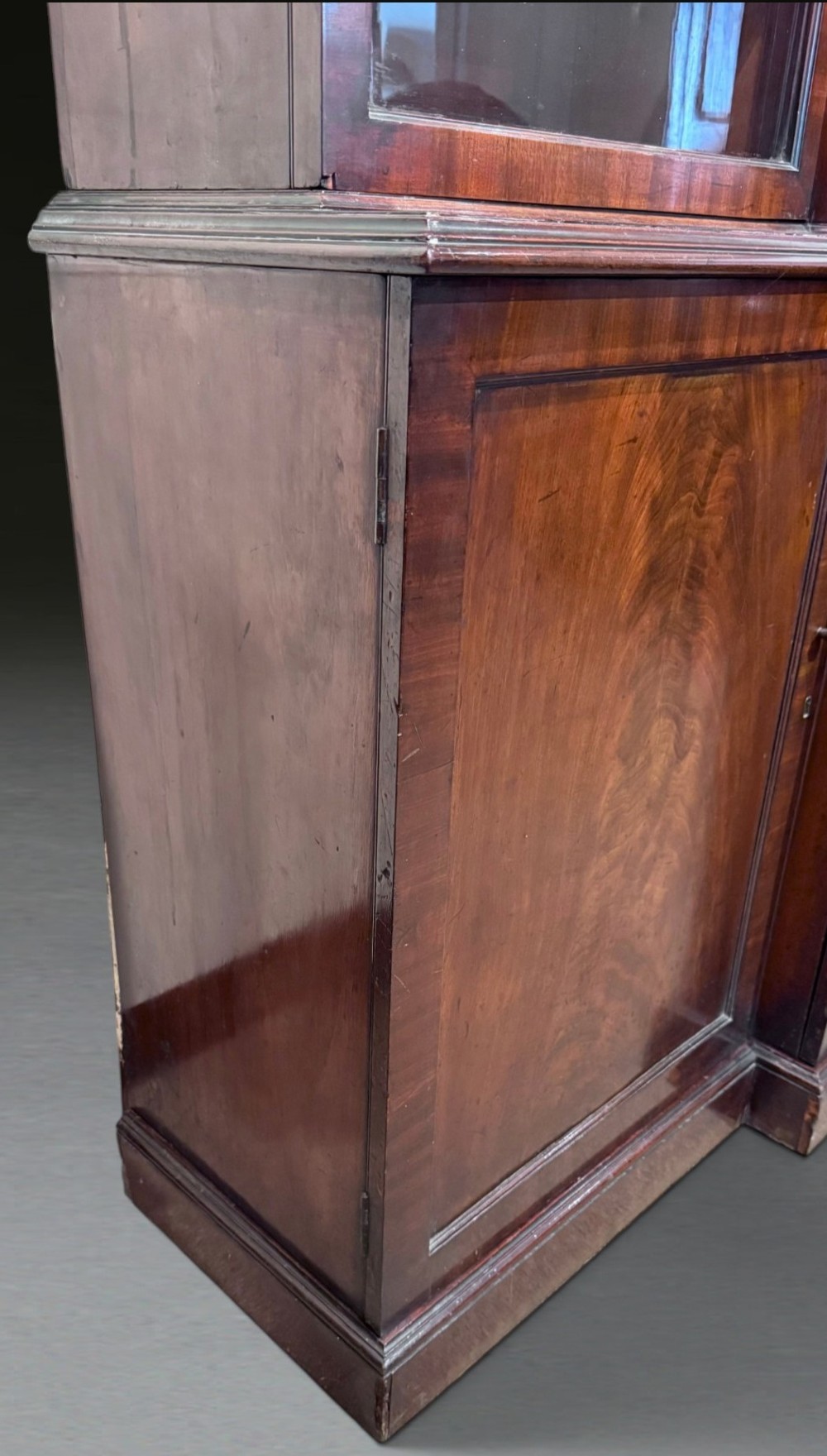 A Georgian flame mahogany breakfront bookcase featuring glazed upper doors and panelled lower cupboard doors. View XII