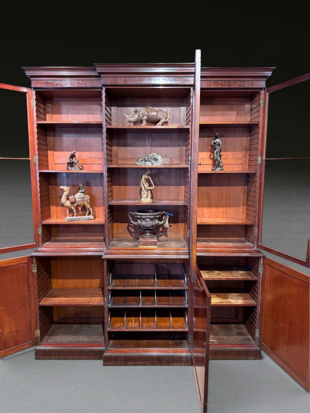A Georgian flame mahogany breakfront bookcase featuring glazed upper doors and panelled lower cupboard doors. View XV