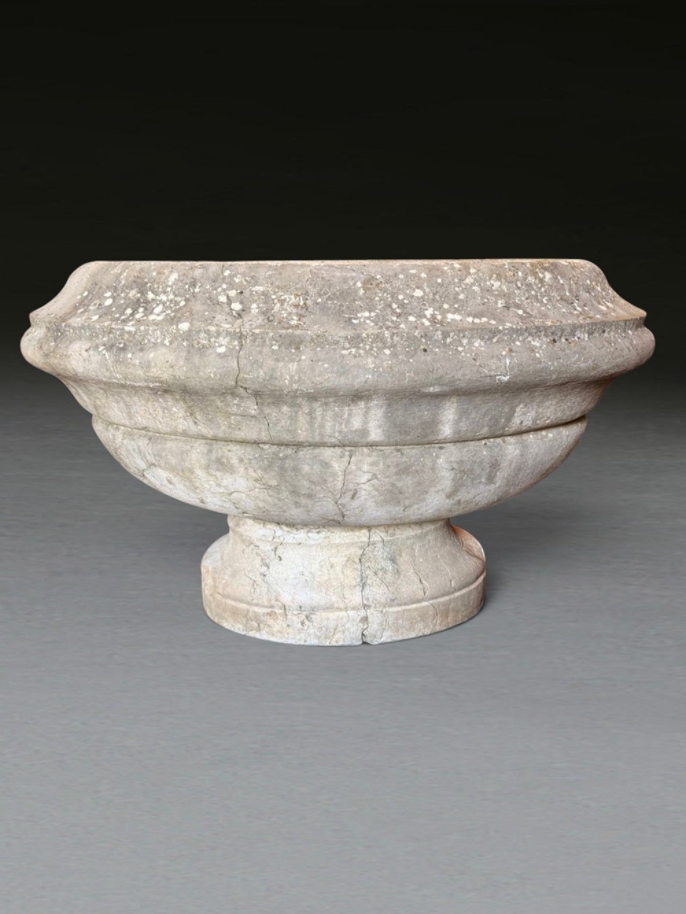 A hand-carved 18th-century grey marble cistern featuring a wide moulded rim and a heavy circular pedestal base. View III
