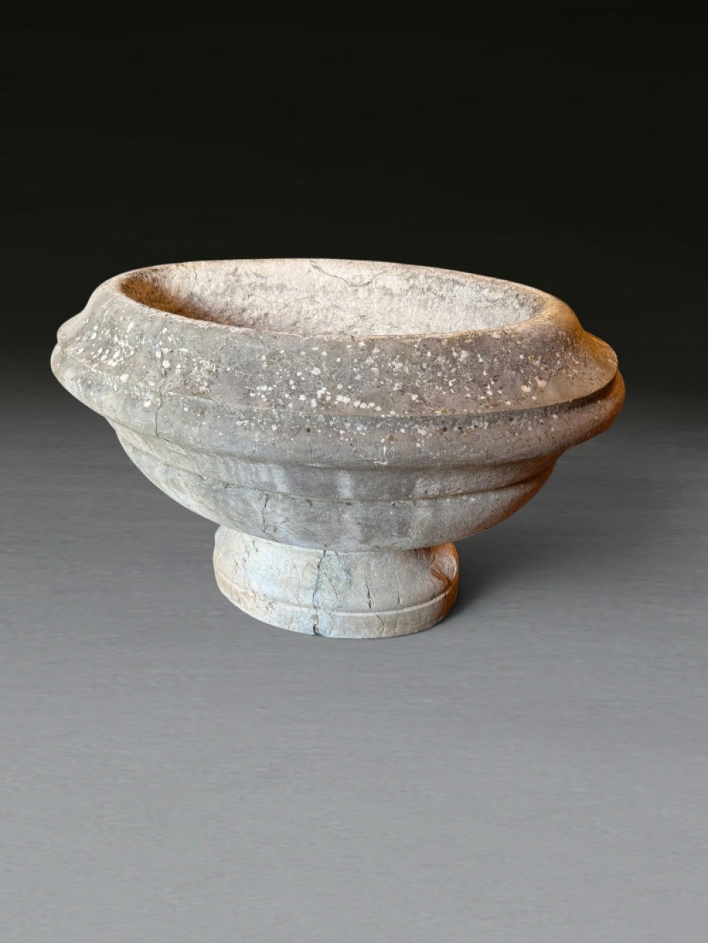 A hand-carved 18th-century grey marble cistern featuring a wide moulded rim and a heavy circular pedestal base. View V