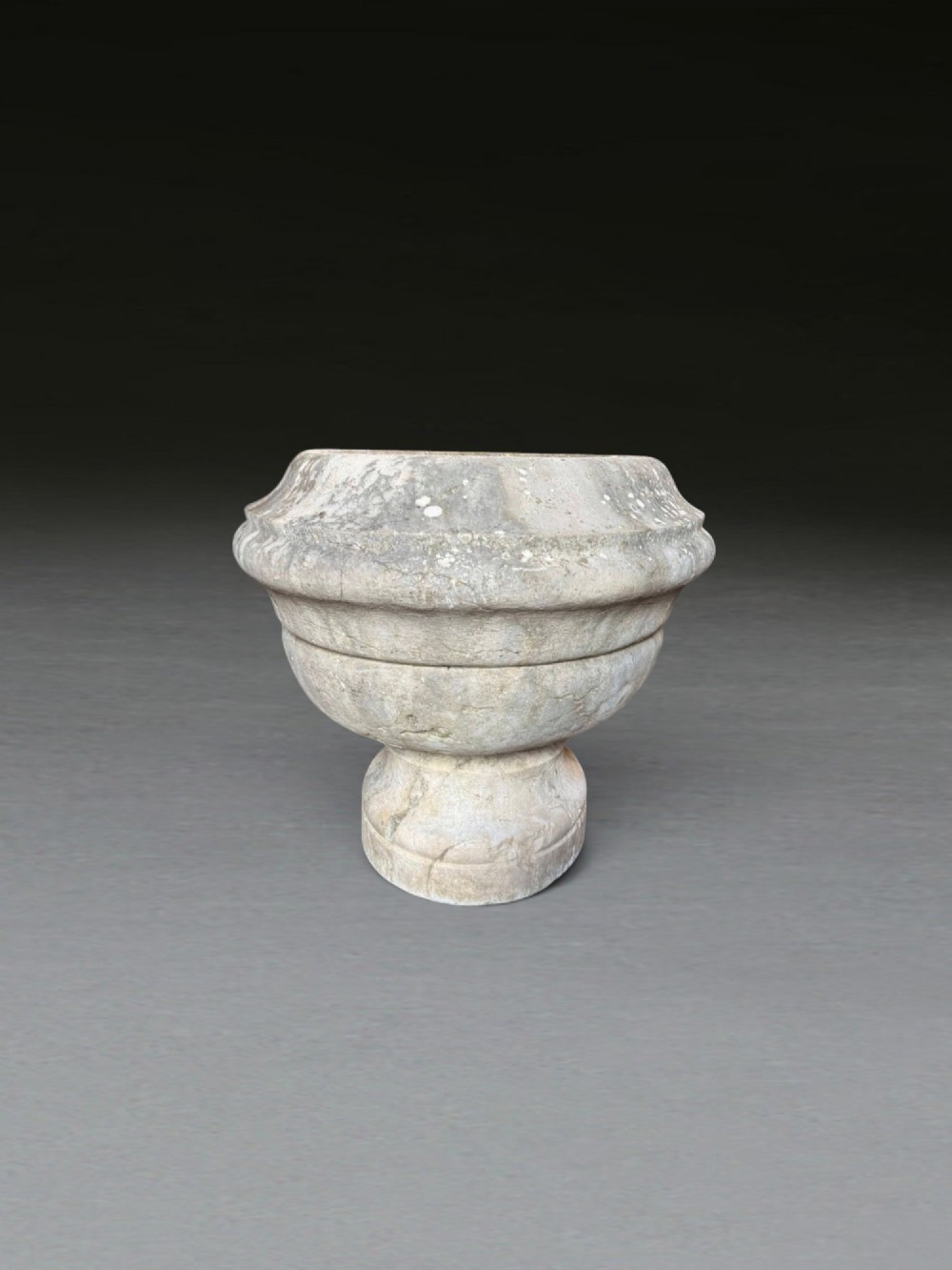 A hand-carved 18th-century grey marble cistern featuring a wide moulded rim and a heavy circular pedestal base. View IX