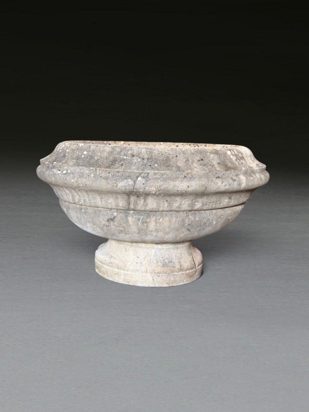 A hand-carved 18th-century grey marble cistern featuring a wide moulded rim and a heavy circular pedestal base. View X
