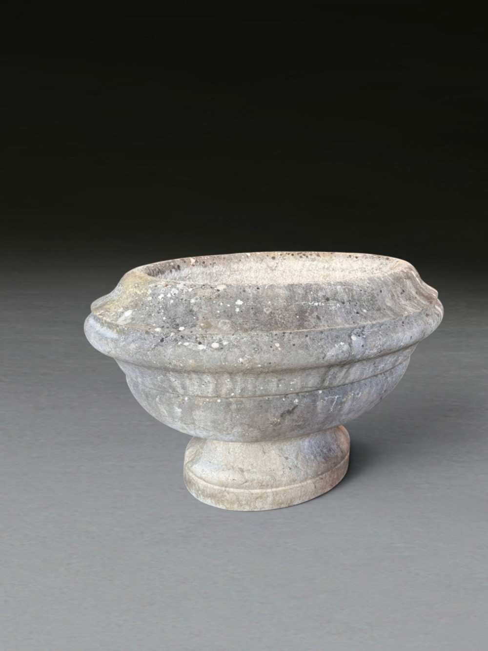 A hand-carved 18th-century grey marble cistern featuring a wide moulded rim and a heavy circular pedestal base. View XI