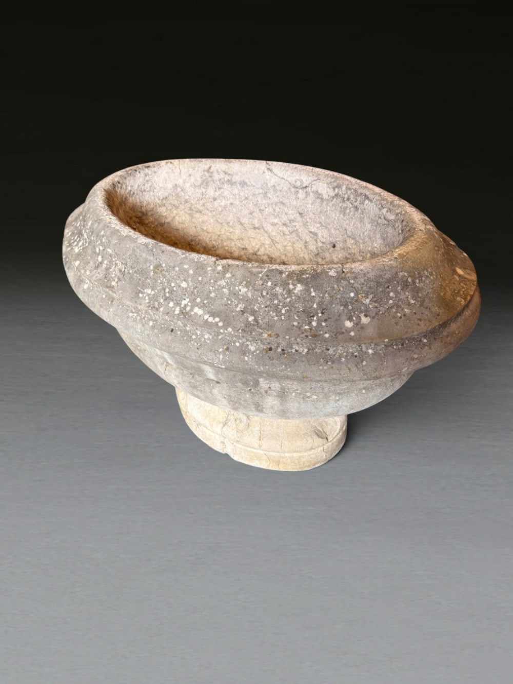 A hand-carved 18th-century grey marble cistern featuring a wide moulded rim and a heavy circular pedestal base. View XII
