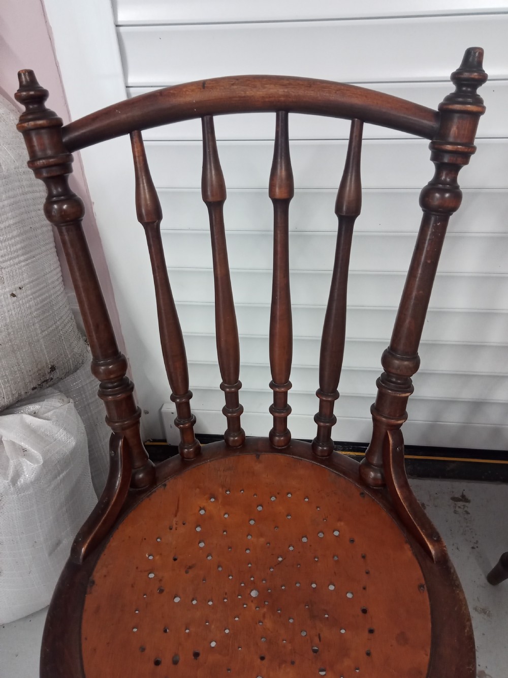 A set of four dark brown Edwardian wooden cafe chairs featuring spindle backs, turned legs, and circular seats with perforated dot patterns. View VI