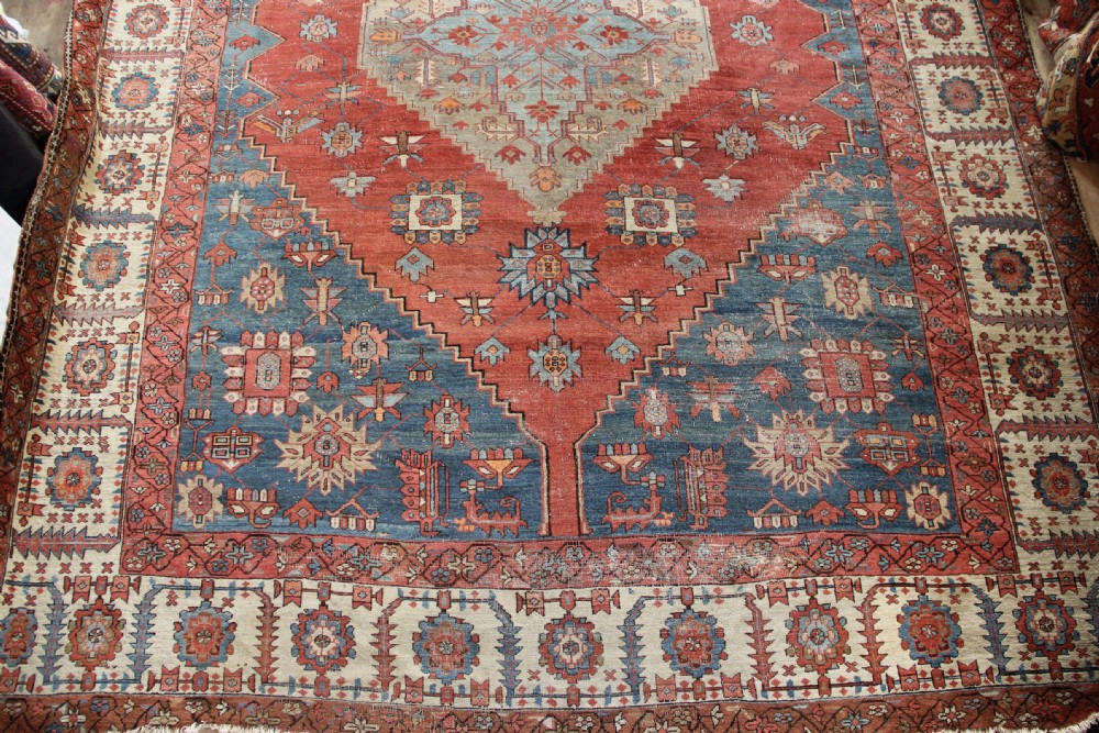 An oversized hand-knotted Persian carpet featuring a central geometric star medallion in light blue and cream on a terracotta field with blue spandrels and patterned borders. View II