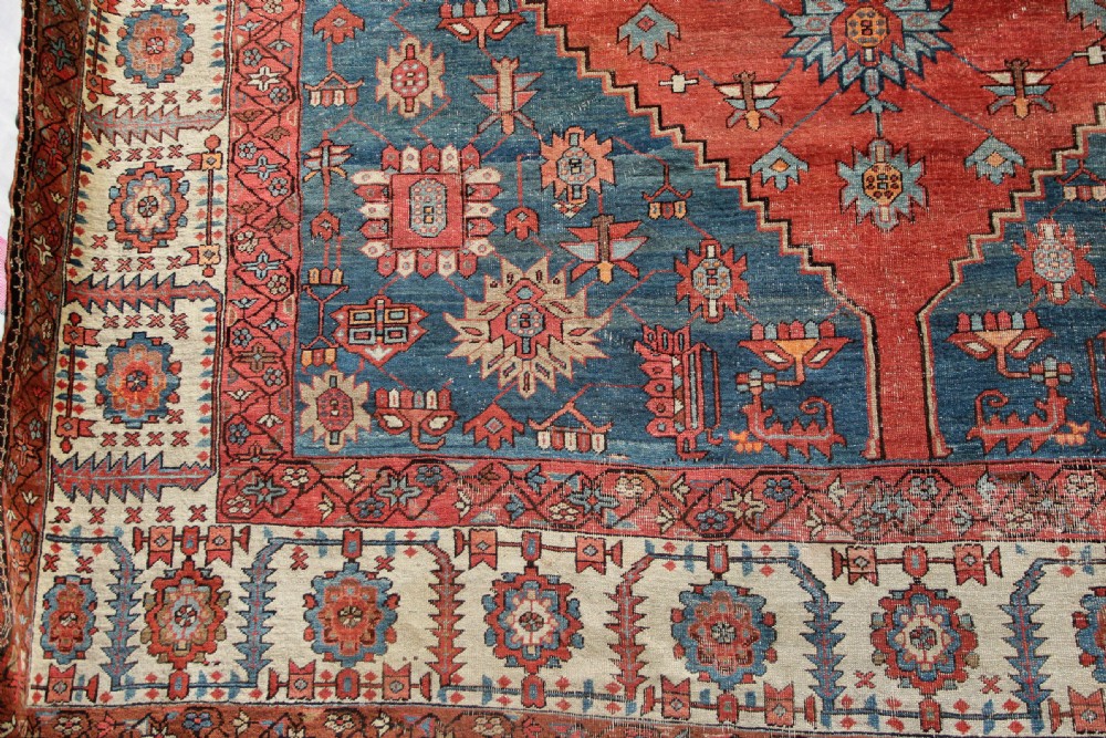 An oversized hand-knotted Persian carpet featuring a central geometric star medallion in light blue and cream on a terracotta field with blue spandrels and patterned borders. View III