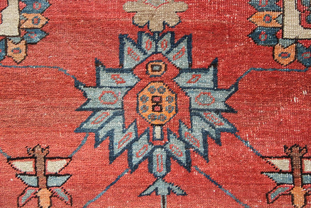 An oversized hand-knotted Persian carpet featuring a central geometric star medallion in light blue and cream on a terracotta field with blue spandrels and patterned borders. View VIII