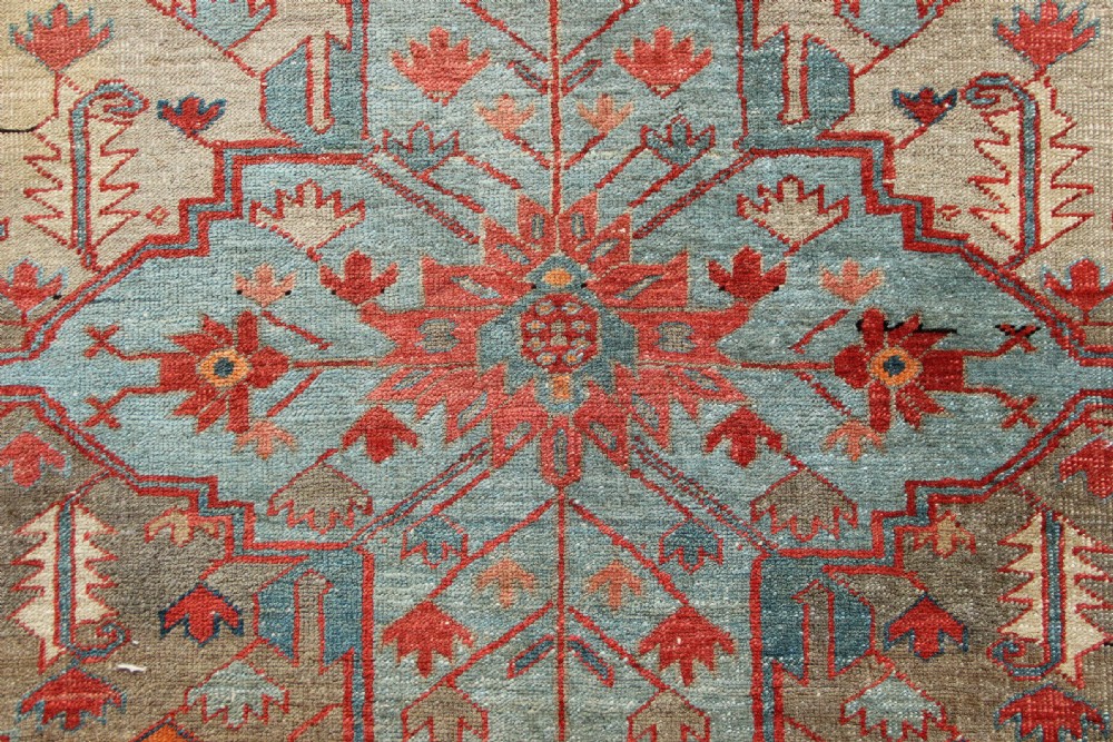 An oversized hand-knotted Persian carpet featuring a central geometric star medallion in light blue and cream on a terracotta field with blue spandrels and patterned borders. View IX