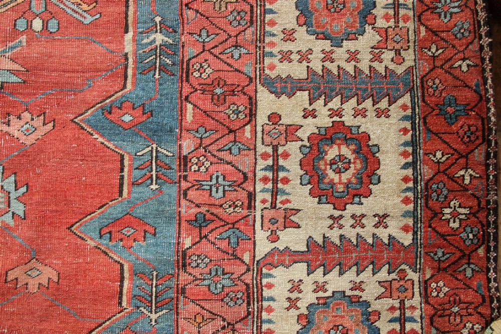 An oversized hand-knotted Persian carpet featuring a central geometric star medallion in light blue and cream on a terracotta field with blue spandrels and patterned borders. View X
