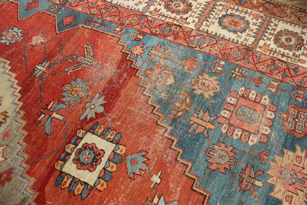 An oversized hand-knotted Persian carpet featuring a central geometric star medallion in light blue and cream on a terracotta field with blue spandrels and patterned borders. View XIII