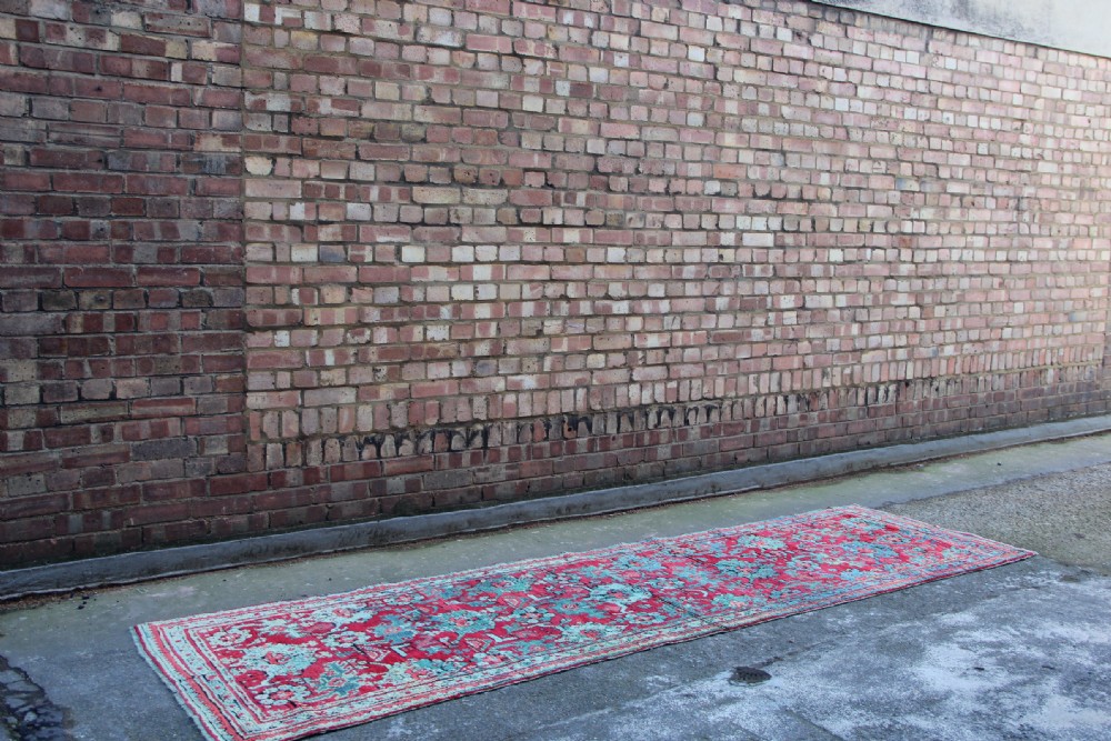 An elongated antique Oushak runner featuring an intricate floral pattern in shades of green and pink on a vibrant ground. View II