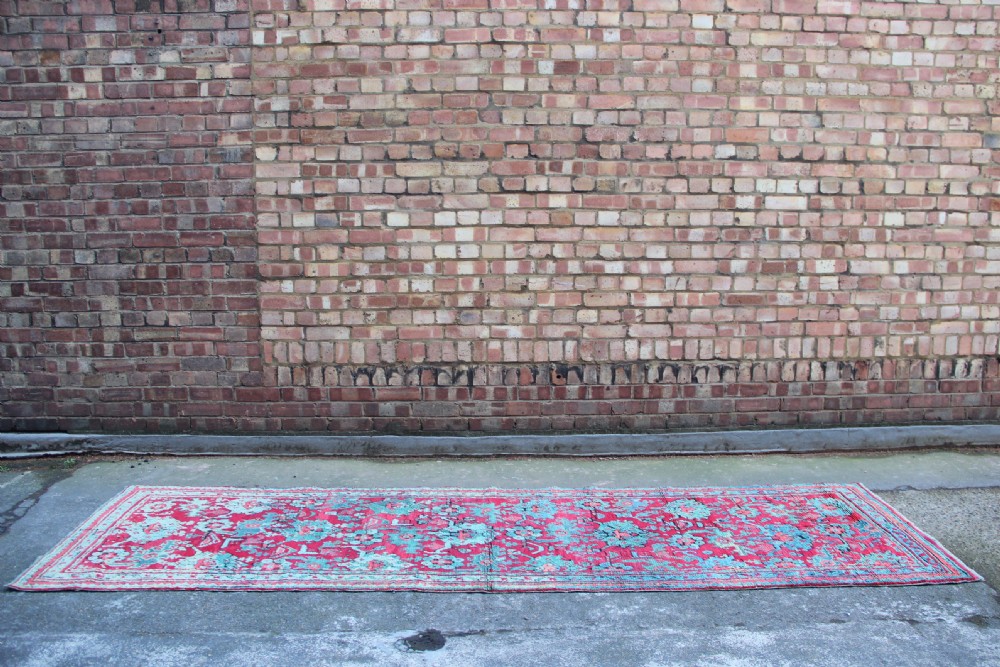 An elongated antique Oushak runner featuring an intricate floral pattern in shades of green and pink on a vibrant ground. View III