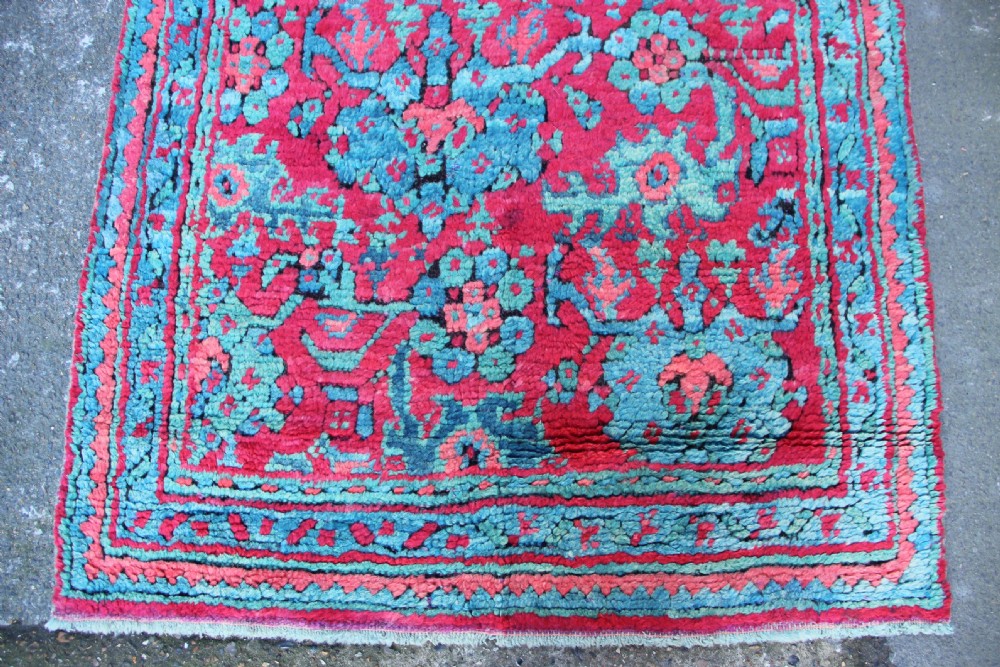An elongated antique Oushak runner featuring an intricate floral pattern in shades of green and pink on a vibrant ground. View V