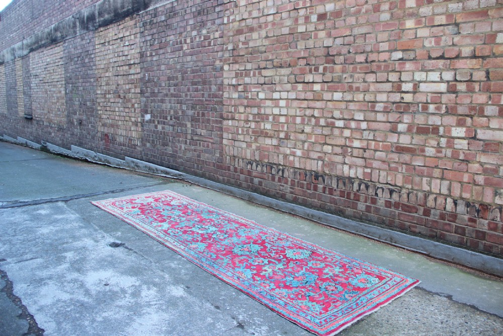 An elongated antique Oushak runner featuring an intricate floral pattern in shades of green and pink on a vibrant ground. View VII