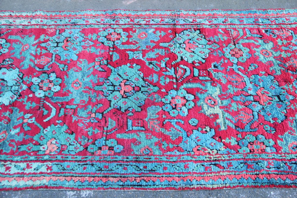 An elongated antique Oushak runner featuring an intricate floral pattern in shades of green and pink on a vibrant ground. View X