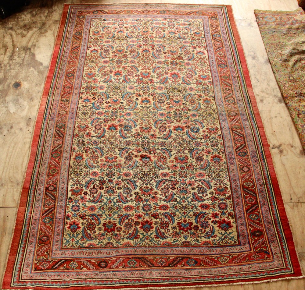 A large hand-knotted antique Bakhshaish wool carpet featuring a dense floral lattice pattern on a cream field surrounded by a terracotta border.