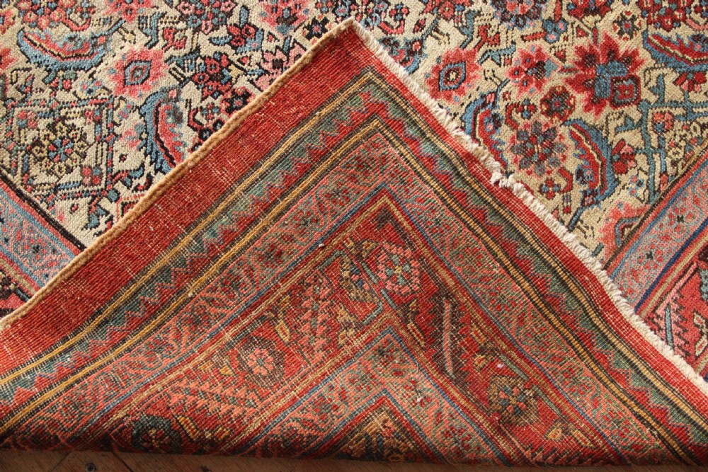 A large hand-knotted antique Bakhshaish wool carpet featuring a dense floral lattice pattern on a cream field surrounded by a terracotta border. View X
