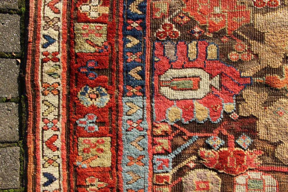 An early nineteenth-century hand-knotted wool Kurdish Sauj Bulagh rug with geometric tribal medallions in terracotta red, blue, and ochre yellow tones. View IV