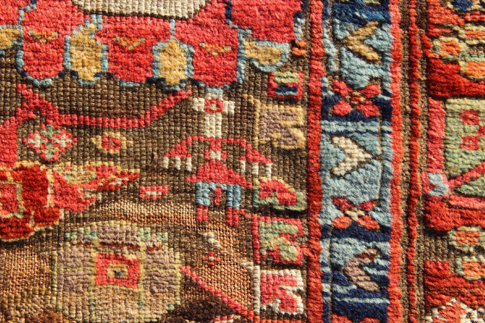 An early nineteenth-century hand-knotted wool Kurdish Sauj Bulagh rug with geometric tribal medallions in terracotta red, blue, and ochre yellow tones. View V