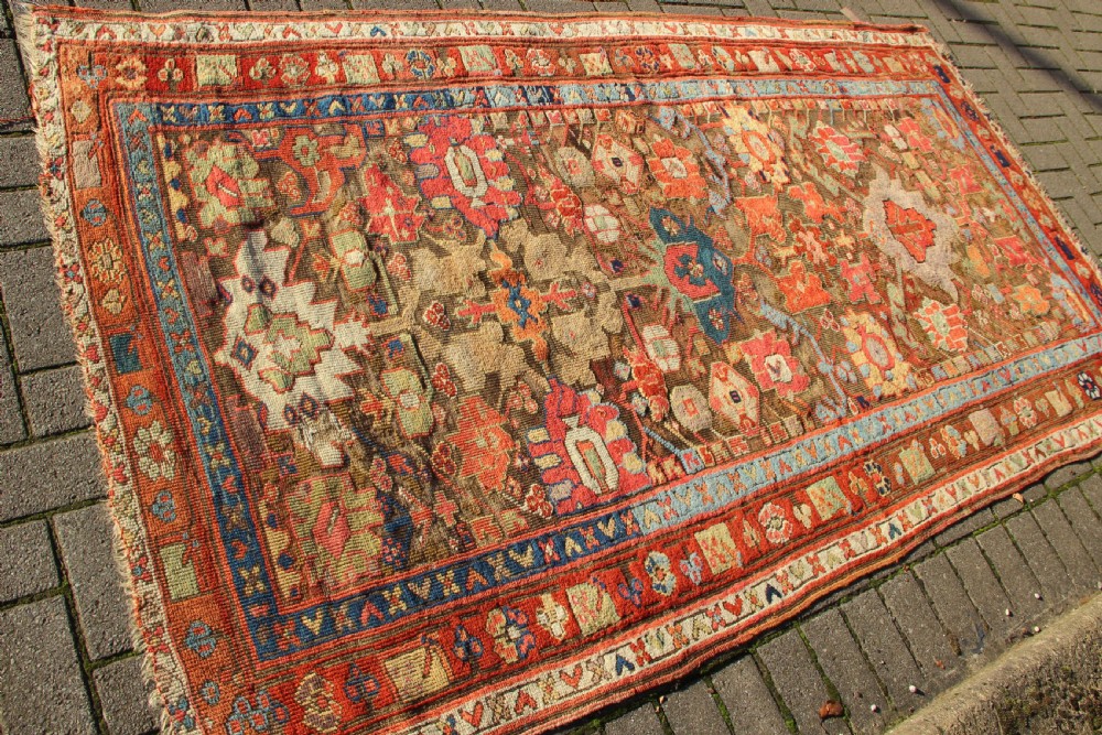 An early nineteenth-century hand-knotted wool Kurdish Sauj Bulagh rug with geometric tribal medallions in terracotta red, blue, and ochre yellow tones. View VIII
