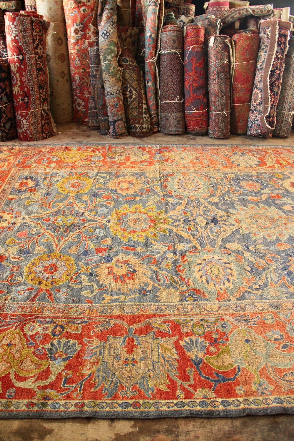 A large hand-knotted antique Ziegler carpet featuring a slate-blue field with all-over botanical palmettes enclosed by a terracotta floral border. View II