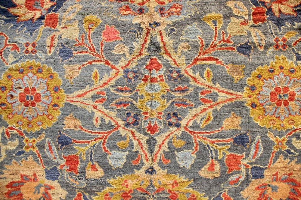 A large hand-knotted antique Ziegler carpet featuring a slate-blue field with all-over botanical palmettes enclosed by a terracotta floral border. View V