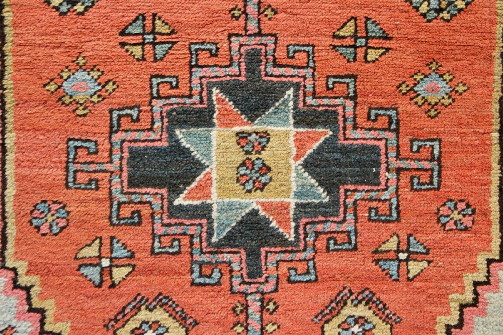 Hand-knotted wool Heriz rug featuring a central terracotta stepped medallion framed by light blue spandrels and patterned borders. View III