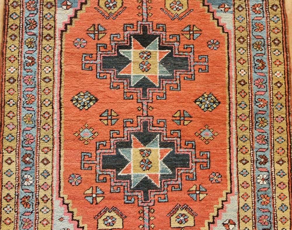 Hand-knotted wool Heriz rug featuring a central terracotta stepped medallion framed by light blue spandrels and patterned borders. View IV