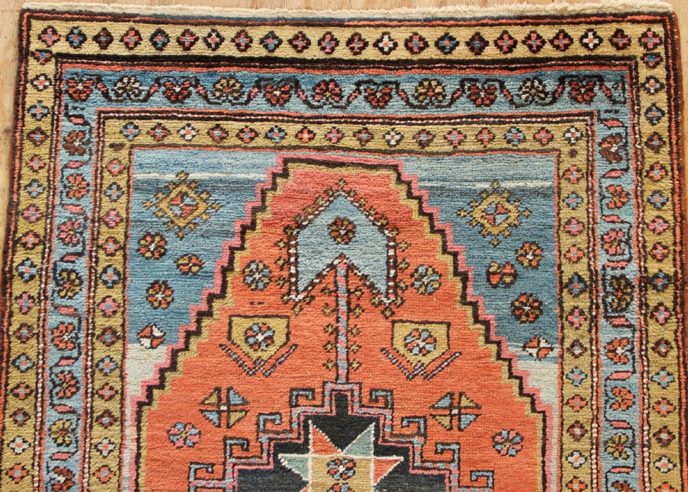 Hand-knotted wool Heriz rug featuring a central terracotta stepped medallion framed by light blue spandrels and patterned borders. View V