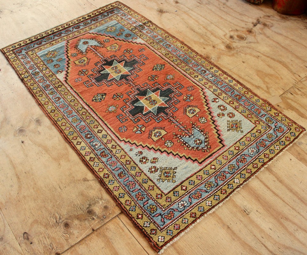 Hand-knotted wool Heriz rug featuring a central terracotta stepped medallion framed by light blue spandrels and patterned borders. View VI