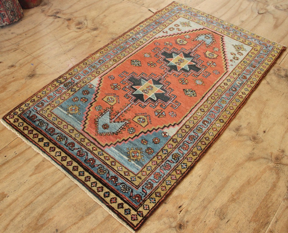 Hand-knotted wool Heriz rug featuring a central terracotta stepped medallion framed by light blue spandrels and patterned borders. View VIII