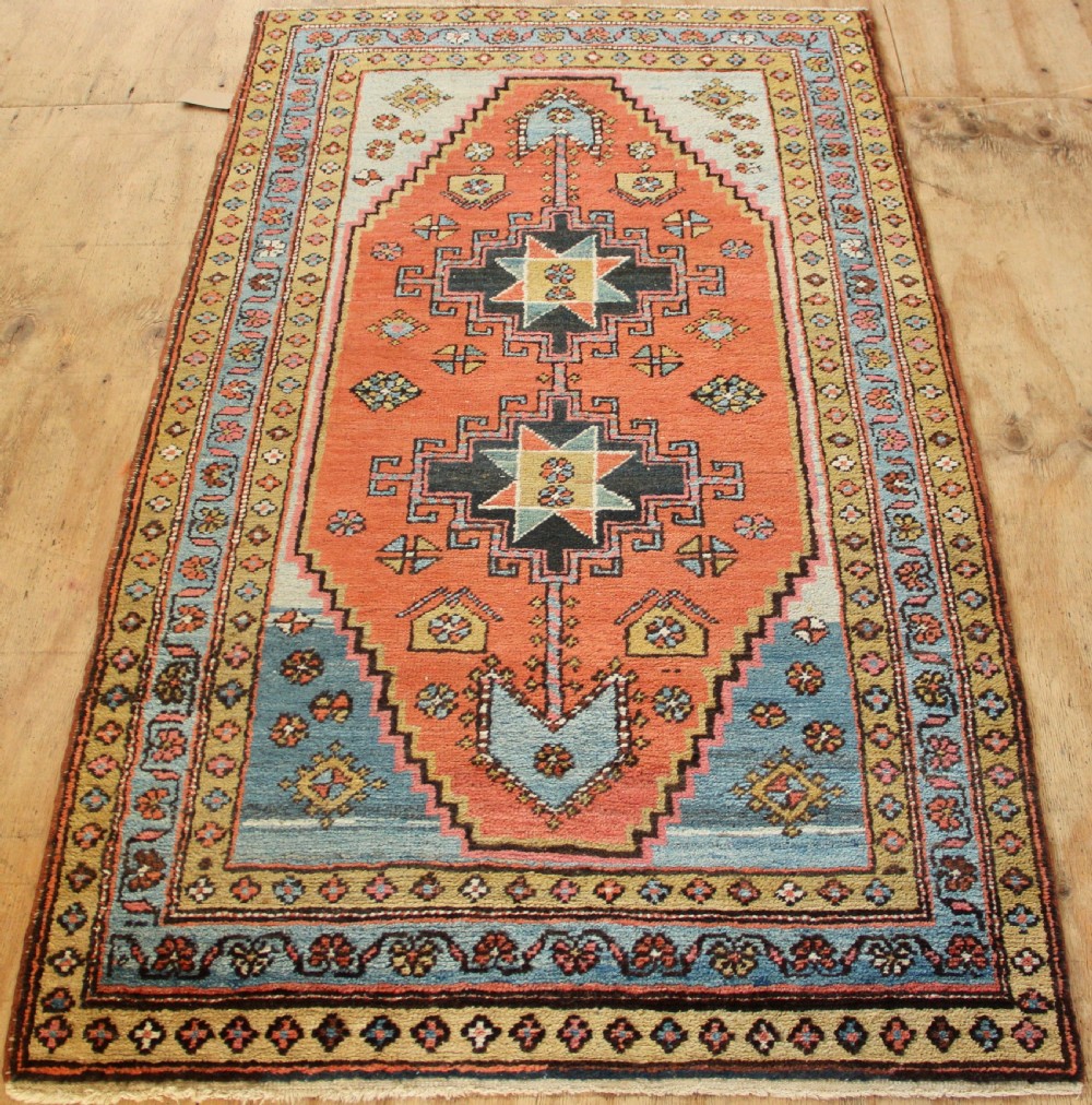 Hand-knotted wool Heriz rug featuring a central terracotta stepped medallion framed by light blue spandrels and patterned borders. View IX