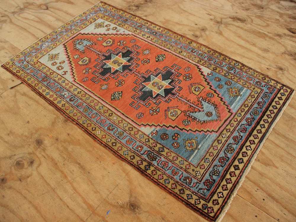 Hand-knotted wool Heriz rug featuring a central terracotta stepped medallion framed by light blue spandrels and patterned borders. View X
