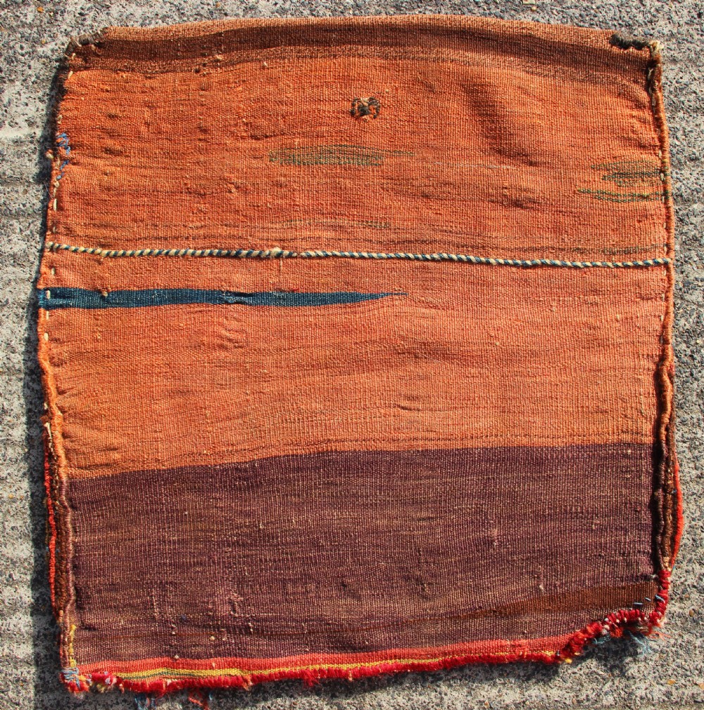 A square antique Kurdish woven saddlebag face displaying geometric borders in blue, red, and yellow surrounding a central medallion with woven bottom loops. View VI