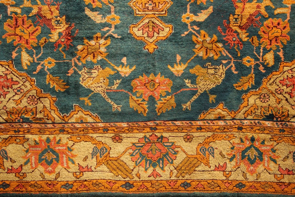 A large hand-knotted antique Oushak wool carpet featuring a central stepped medallion on a teal field surrounded by cream and gold floral borders. View II
