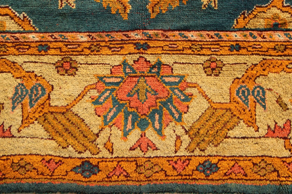 A large hand-knotted antique Oushak wool carpet featuring a central stepped medallion on a teal field surrounded by cream and gold floral borders. View III