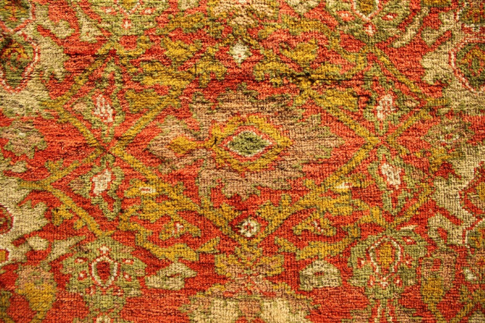 A square hand-knotted antique Ziegler wool carpet featuring a terracotta red field filled with intricate floral palmettes and framed by multi-tiered decorative borders. View VI